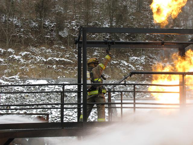 Instructor N. Smith closes the valve while being protected by his student's hose streams